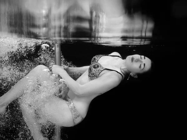 黒い背景のスイミングプールで水中ポールを持つ水泳クリスタルブラジャーとパンツの若い フィット スリムな女性のモノクロの肖像画 — ストック写真