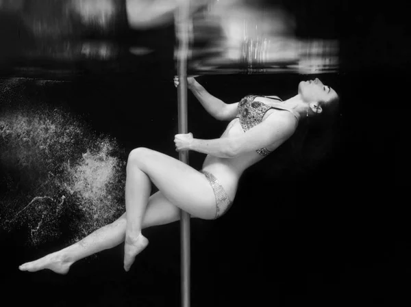 黒い背景のスイミングプールで水中ポールを持つ水泳クリスタルブラジャーとパンツの若い フィット スリムな女性のモノクロの肖像画 — ストック写真