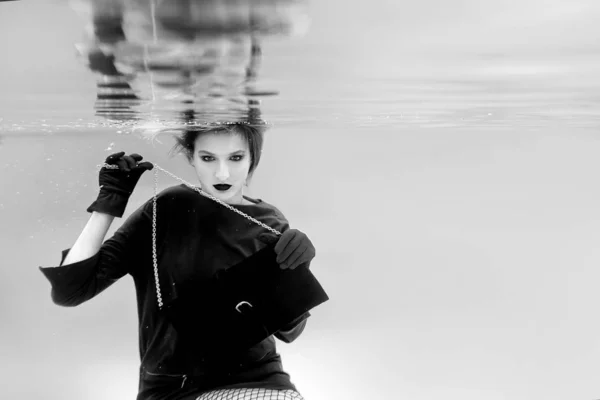 单色肖像的美丽惊人的时尚漂亮的年轻女子在礼服 黑色离合器袋和紧身衣在游泳池的水下网 艺术和购物理念 — 图库照片