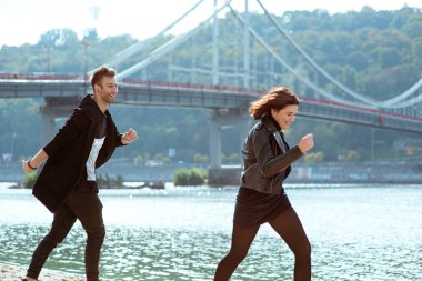 güzel şaşırtıcı komik neşeli genç çift (adam ve kadın) köprü arka planda nehir tarafından açık çalışan. Kız arkadaşı ve erkek arkadaşı. Aile, eğlence, aşk ve dostluk konsepti