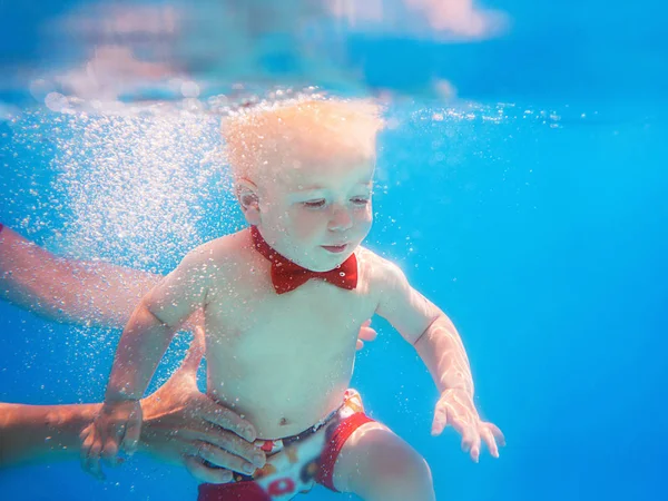 スイミングプールで水中に潜る赤い蝶の幼児は 泳ぐことを学びます スポーツと休暇のコンセプト — ストック写真