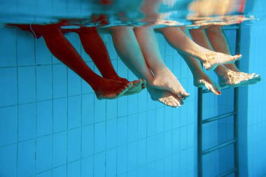 yüzme havuzunda dört kişi ayak lar su altında. Parti. Yaz. Tatil, çeşitlilik, dostluk ve spor konsepti.