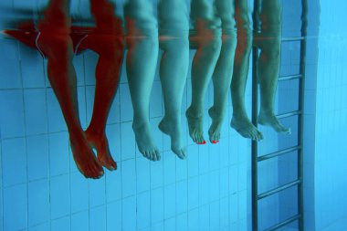 yüzme havuzunda dört kişi ayak lar su altında. Parti. Yaz. Tatil, çeşitlilik, dostluk ve spor konsepti.
