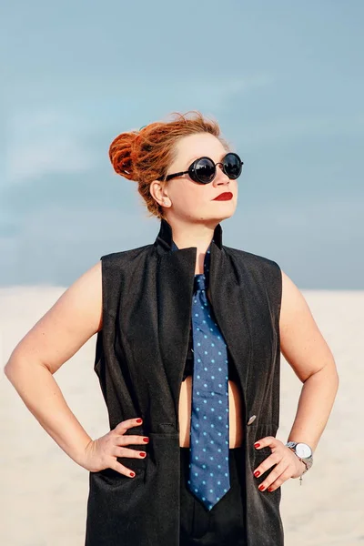 crazy funny grunge punk redhead woman with dreadlocks in office clothes and sunglasses in the desert