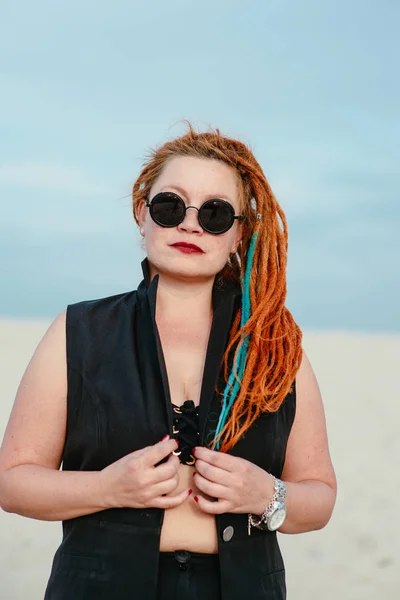 crazy funny grunge punk redhead woman with dreadlocks in office clothes and sunglasses in the desert