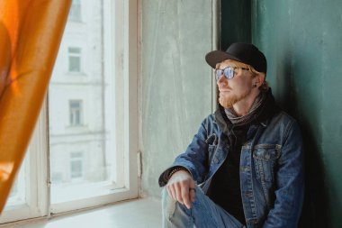 siyah şapka ve Jean ceket ve gözlük tek başına pencerede modern kızıl yakışıklı şık adam portresi. Moda konsepti