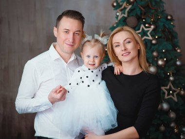 Mutlu Kafkas ailesi (baba, anne ve küçük kızı) evdeki noel ağacının yanında. Noel ve Yeni Yıl Konsepti