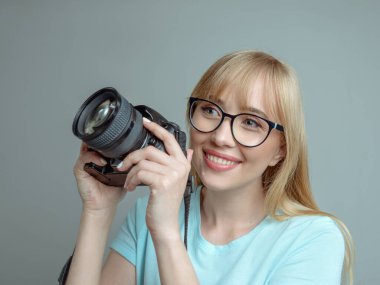 blonde stylish cheerful woman photographer in glasses and holding photo camera. Hobby, work, shooting concept