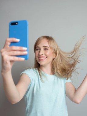 Şık, güzel sarışın blog yazarı akıllı telefonuyla selfie çekiyor. Eğilim, teknoloji, güzellik, moda kavramı