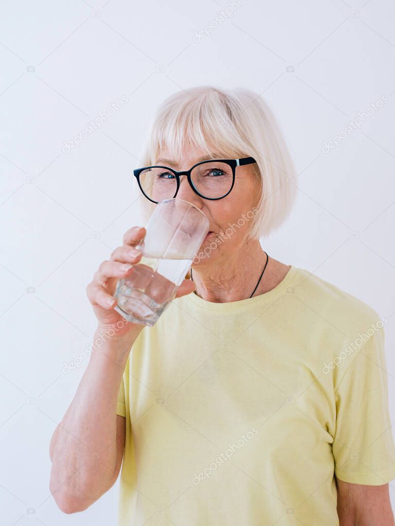 senior woman holding glass of water and drinking water. Healthy lifestyle, sport, anti age concept