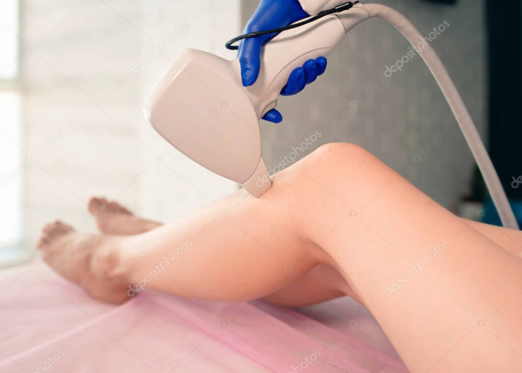 Beautiful smooth woman's legs while laser hair removal on cosmetologists office background. Beauty, treatment, hair removal concept