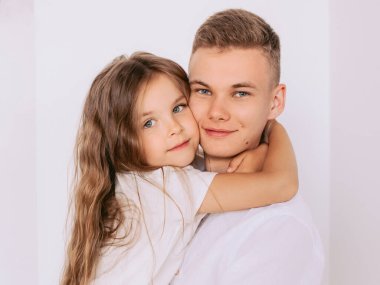 Kafkasyalı mutlu sevimli kardeşler. Genç erkek kardeş ve küçük kız kardeş. Beyaz arka planda kucaklaşıyorlar. Aile, ilişkiler, akrabalar, aşk, destek kavramı