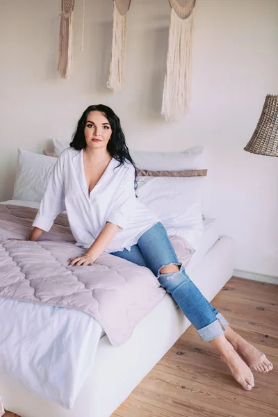 셔츠와 청바지를 아름다운 여자의 초상화가 침대에 모습을 — 스톡 사진