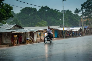 Yongoro, Sierra Leone - 04 Haziran 2013: Batı Afrika, motosiklet yağmur sırasında bilinmeyen adam yola Yongoro için Sierra Leone, Freetown sermaye önünde giden yeni bir yol