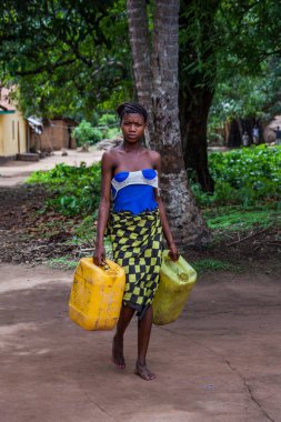 Yongoro, Sierra Leone - 04 Haziran 2013: Batı Afrika, bilinmeyen kadın Sierra Leone, Freetown başkenti önünde köye su dolu kutu taşır