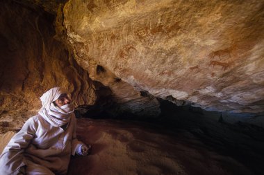 Tamanrasset, Algeria - 7 Ocak 2002: Sahra Çölü, Wilaya Tamanrasset, Hoggar Dağları, Cezayir, Afrika hayvanlarda çizimlerinin antik kaya önemini açıklayan bilinmeyen Touareg kılavuzları