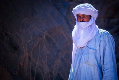 Tamanrasset, Algeria - 7 Ocak 2002: Sahra Çölü, Wilaya Tamanrasset, Hoggar Dağları, Cezayir, Afrika hayvanlarda çizimlerinin antik kaya önemini açıklayan bilinmeyen Touareg kılavuzları