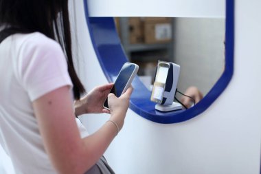 Yetişkin bir kadının, aletini kullanarak para vermeden yaptığı alışverişin fotoğrafını çek.