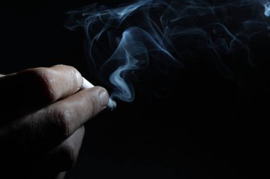 El ele tutuşan sigara ve duman izole siyah arka plan