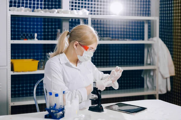 examining a tissue section for evidence of cancerous cells. a focused student-science works in a lab with a petri dish. Chemistry. Biology. Analyzes. Virus.