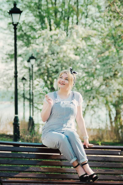 Bir kız eline kiraz çiçekleri bir delikanlı ile bir bankta oturuyor. O doğa hayran ve güneşli gün sahiptir.