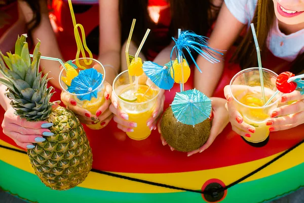 Yaz kız ellerinde şemsiyelerle narenciye kokteyller. Limonata yenileniyor. Yukarıdan görüntüleyin. Parlak renk. Hindistan cevizi içki.