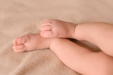 Yeni doğan küçük bacaklarını kapat. Bebek ayakları bir halı üzerinde.