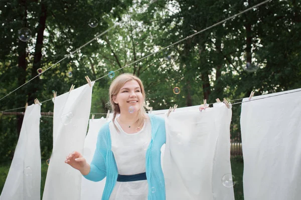 Genç kadın Bahçe Beyaz (temiz) çarşaf asmak. Yerli r