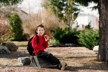 Okula geri dön. Arkasında sırt çantası olan kırmızı bir kazak giyen bir çocuk.