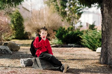 Okula geri dön. Arkasında sırt çantası olan kırmızı bir kazak giyen bir çocuk.