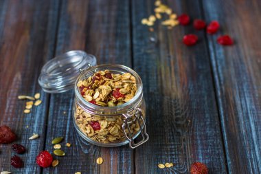 Granola yoğurt, kurutulmuş meyveler ve koyu ahşap masa üzerinde kabak çekirdeği