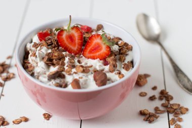 Granola yoğurt, pembe bir kase çilek ile sağlıklı kahvaltı.