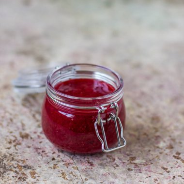 Masadaki cam kavanozda çilek reçeli.