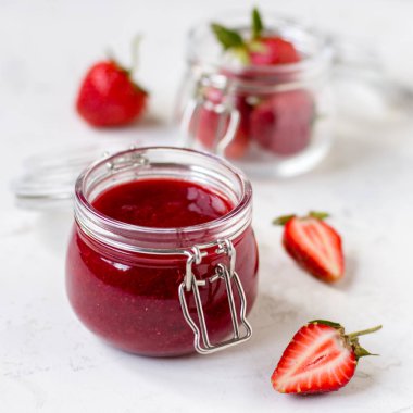 Masadaki cam kavanozda çilek reçeli.