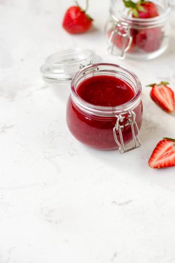 Masadaki cam kavanozda çilek reçeli.