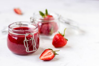 Masadaki cam kavanozda çilek reçeli.