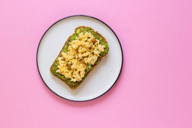 Kepekli ekmek ile avokado, pembe bir arka plan üstten görünüm üzerinde yumurta.