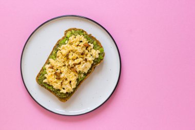 Kepekli ekmek ile avokado, pembe bir arka plan üstten görünüm üzerinde yumurta.