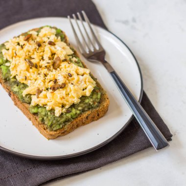 Sahanda yumurta üzerinde avokado ile kepekli ekmek.