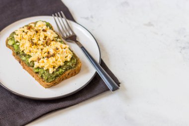 Sahanda yumurta üzerinde avokado ile kepekli ekmek.