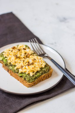 Sahanda yumurta üzerinde avokado ile kepekli ekmek.