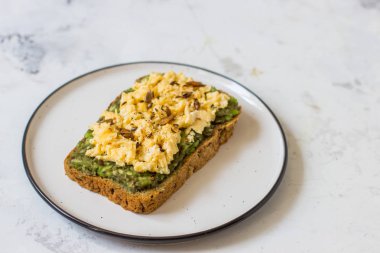 Sahanda yumurta üzerinde avokado ile kepekli ekmek.