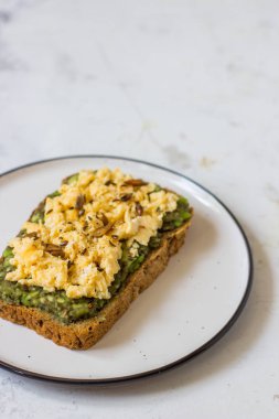 Sahanda yumurta üzerinde avokado ile kepekli ekmek.