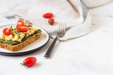 Omlet ve avokado ve kiraz domates ile kepekli ekmek üzerinde.