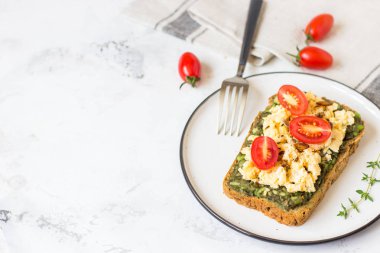 Omlet ve avokado ve kiraz domates ile kepekli ekmek üzerinde.