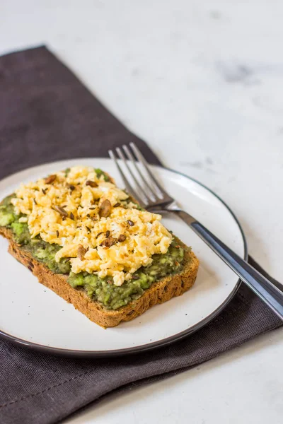 Sahanda yumurta üzerinde avokado ile kepekli ekmek.