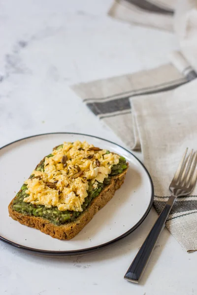 Sahanda yumurta üzerinde avokado ile kepekli ekmek.