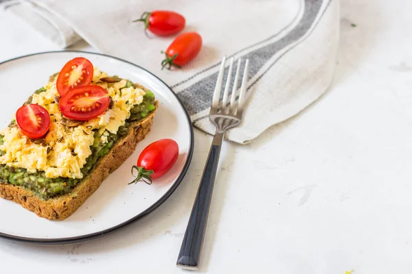 Omlet ve avokado ve kiraz domates ile kepekli ekmek üzerinde.