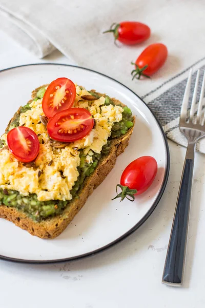 Omlet ve avokado ve kiraz domates ile kepekli ekmek üzerinde.