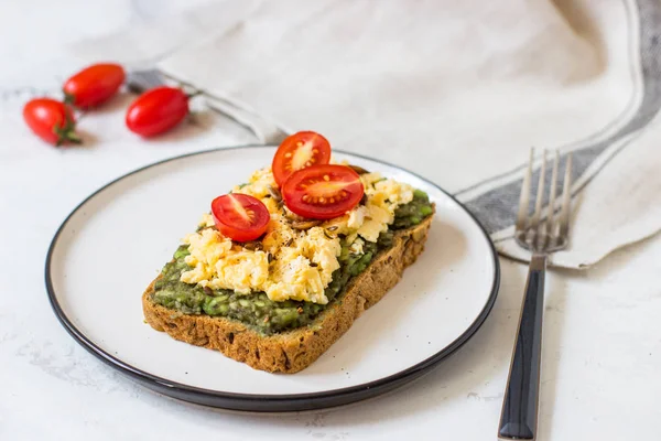 Omlet ve avokado ve kiraz domates ile kepekli ekmek üzerinde.